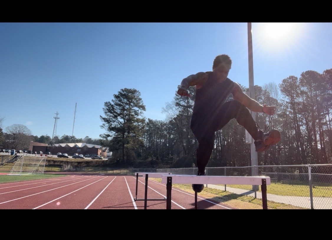 Frank Monroe practicing a hurdle jump outdoors